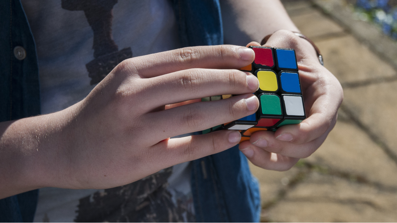 A boy's hands as he plays with a rubiks cube