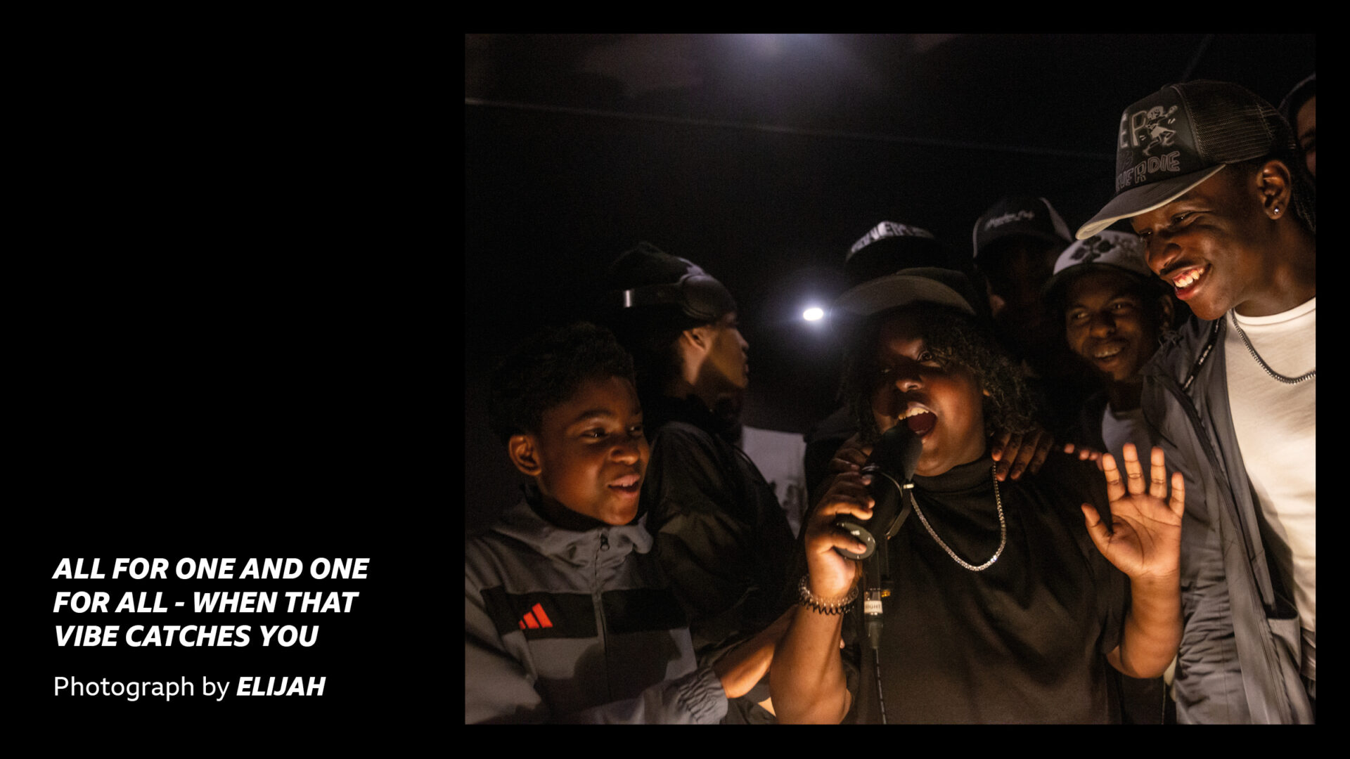 'All for one and one for all - when that vibe catches you - photograph by Elijah' - young people rapping together in a dark studio room