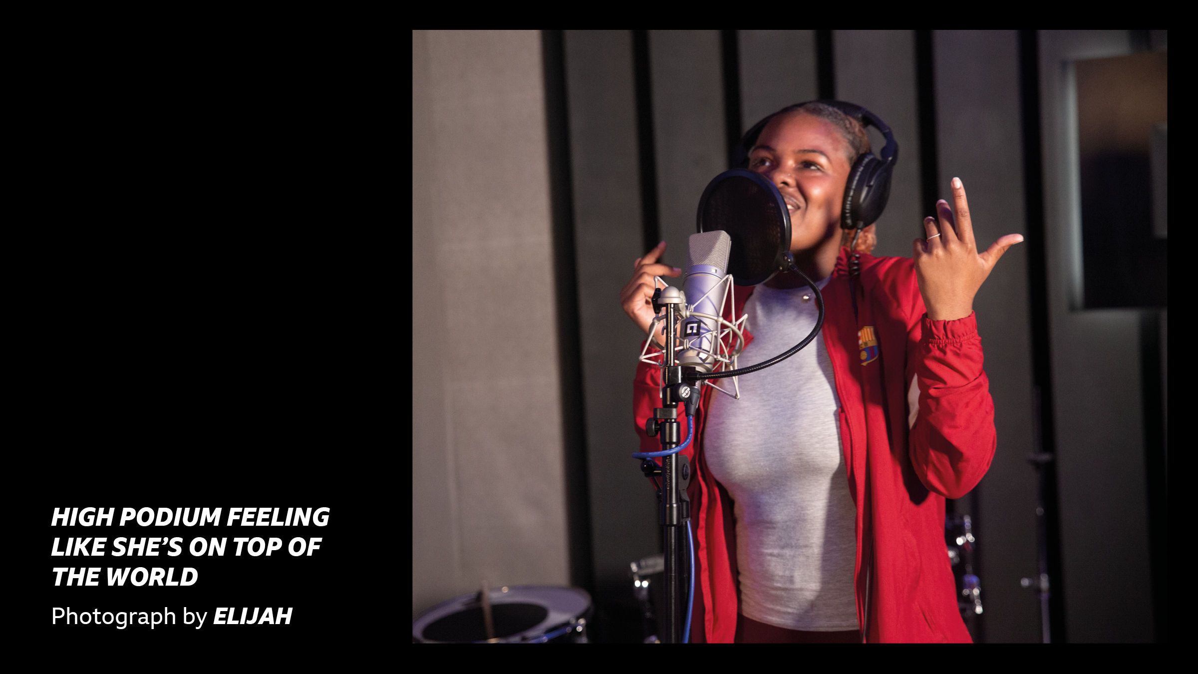 'High Podium feeling like she's on top of the world - Photograph by Elijah' - A young woman rapping into a microphone in a studio