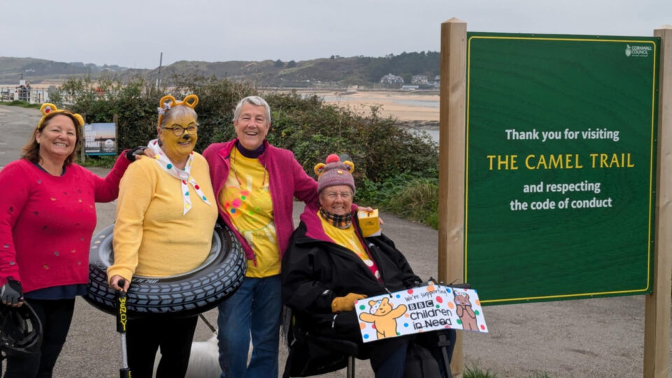 Wendy and her team next to a trail sign